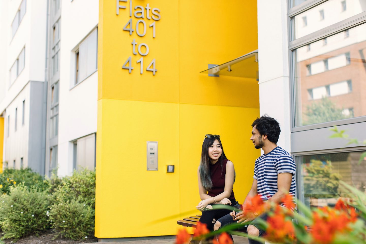 Students sitting on a bench in front of the student dorm