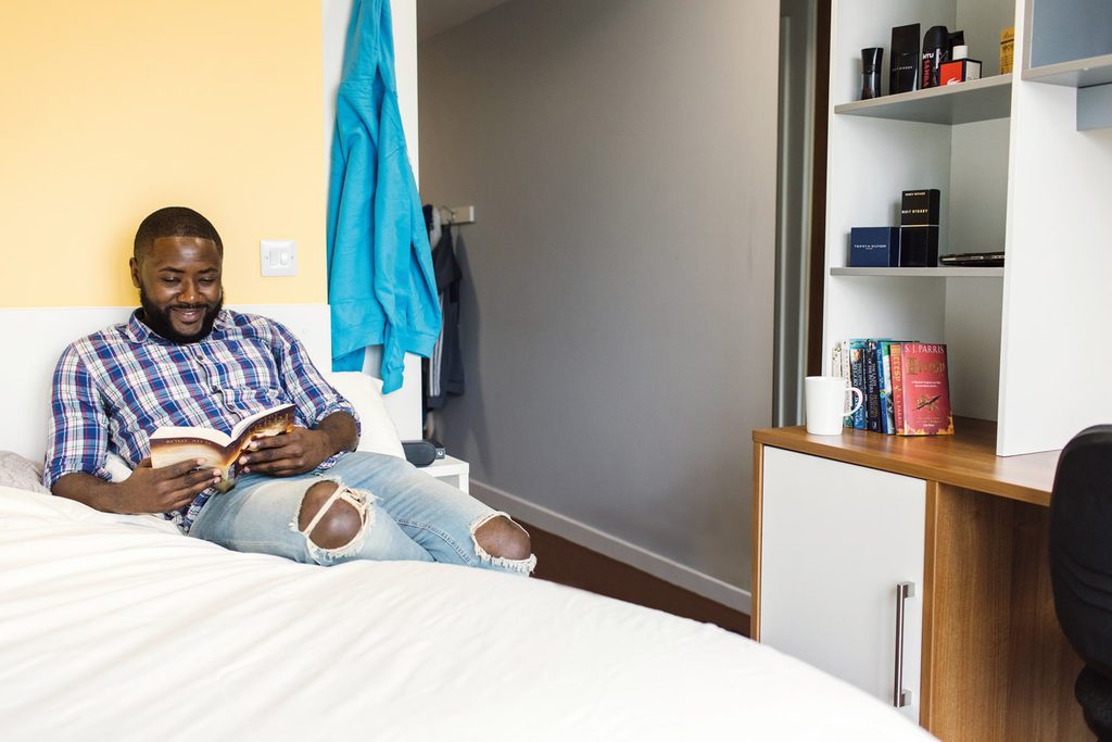 Student lying on his bed and reading a book