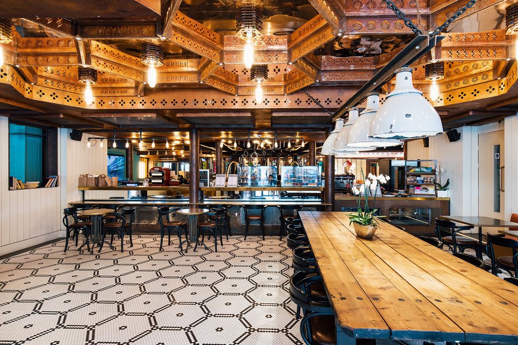 A social space with long tables and a café at The Stay Club Kentish Town in London