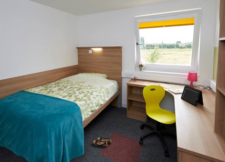A bed and a study desk in a premium ensuite at the Meadows