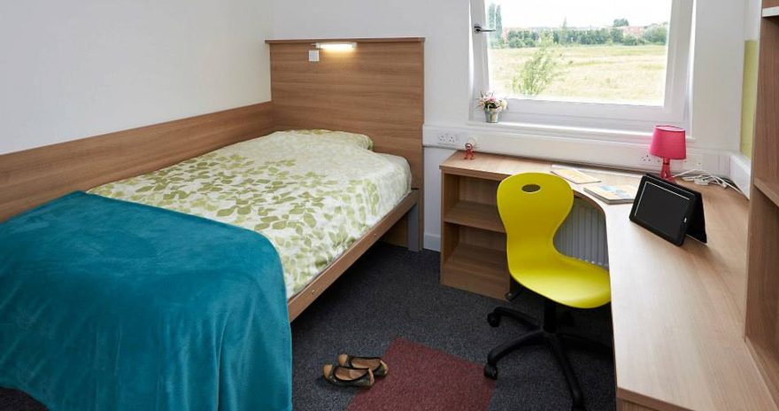 A bed and a study desk in a premium ensuite at the Meadows