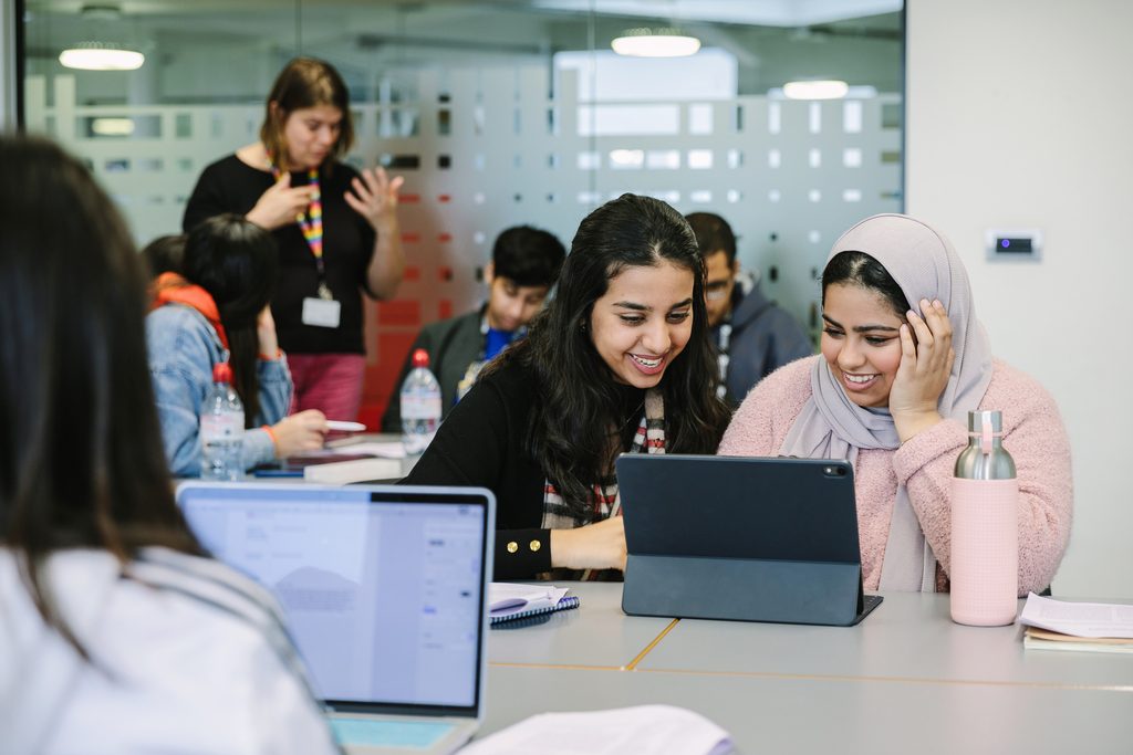 Two students studying over a tablet