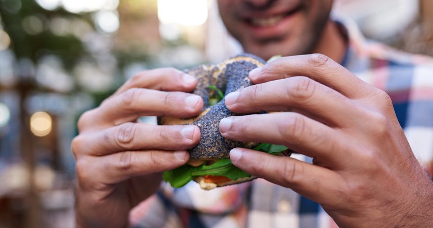 A man with a smiling face holding a bagel