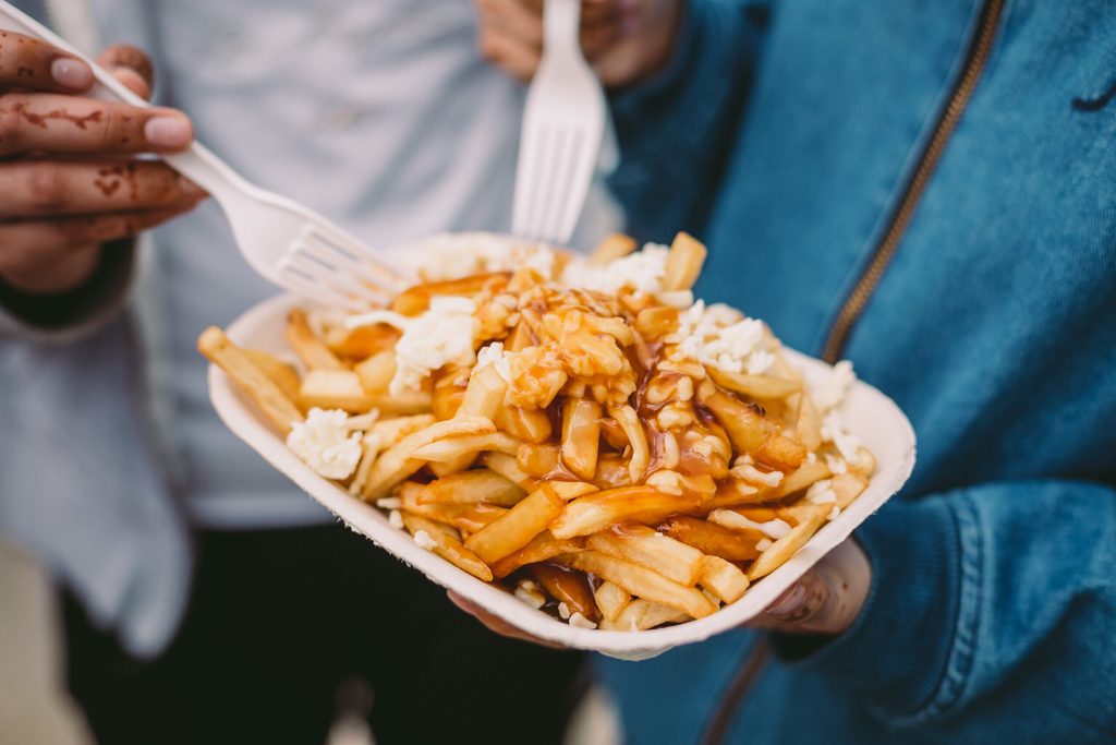 Two friends eating take away poutine